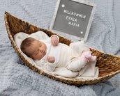 Neugeborenes Baby in einem Korb, umgeben von einer Decke, mit einem Schild, das "Willkommen Erika Maria" zeigt.