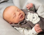 Ein schlafendes Baby in einem grauen Strampler mit einem Winnie-Pooh-Motiv, eingekuschelt in eine weiche Decke.