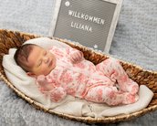 Neugeborenes Baby in einem Korb, trägt einen rosa Schlafanzug mit Blumenmuster. Neben dem Baby steht ein Schild mit der Aufschrift "Willkommen Liliana".