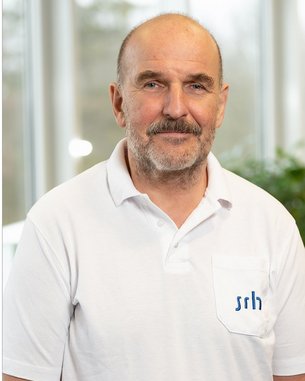 Ein Mann mit einem kurzen Bart trägt ein weißes Poloshirt mit einem blauen Logo auf der Brust. Er steht vor einem hellen Hintergrund mit unscharfen Fenstern. Der Name "Dr. med. Conny-Ullrich Günther" ist darunter angegeben.
