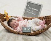 Neugeborenes Baby liegt in einem geflochtenen Korb, umgeben von einem Spielzeug und einem Schild mit der Aufschrift "Willkommen Lia Florentine" sowie dem Datum "07. Juni".